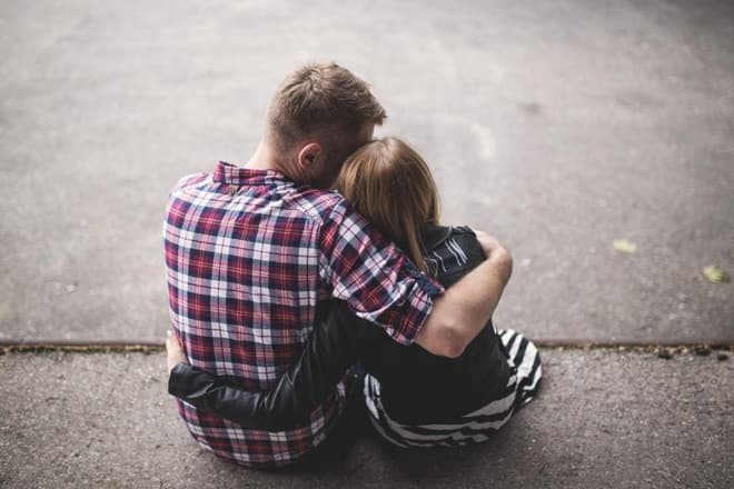 A couple hugging, sitting on the pavement