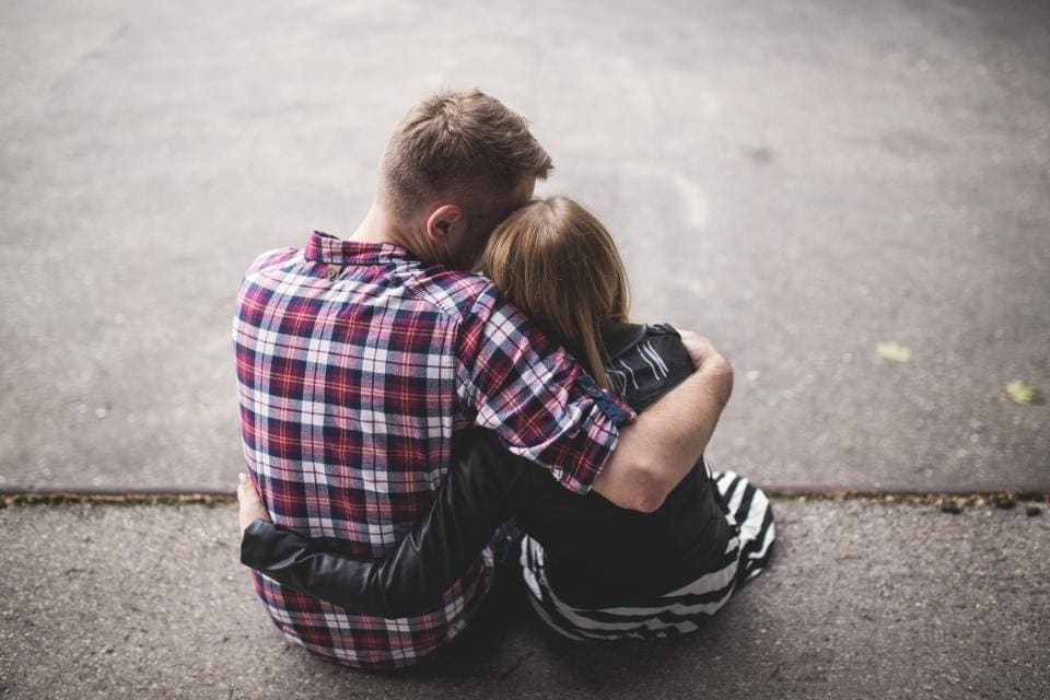 A couple hugging, sitting on the pavement