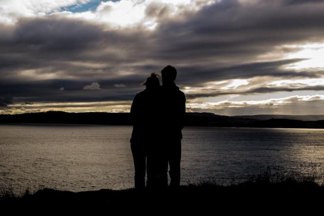 A couple by the lake watching the sunset