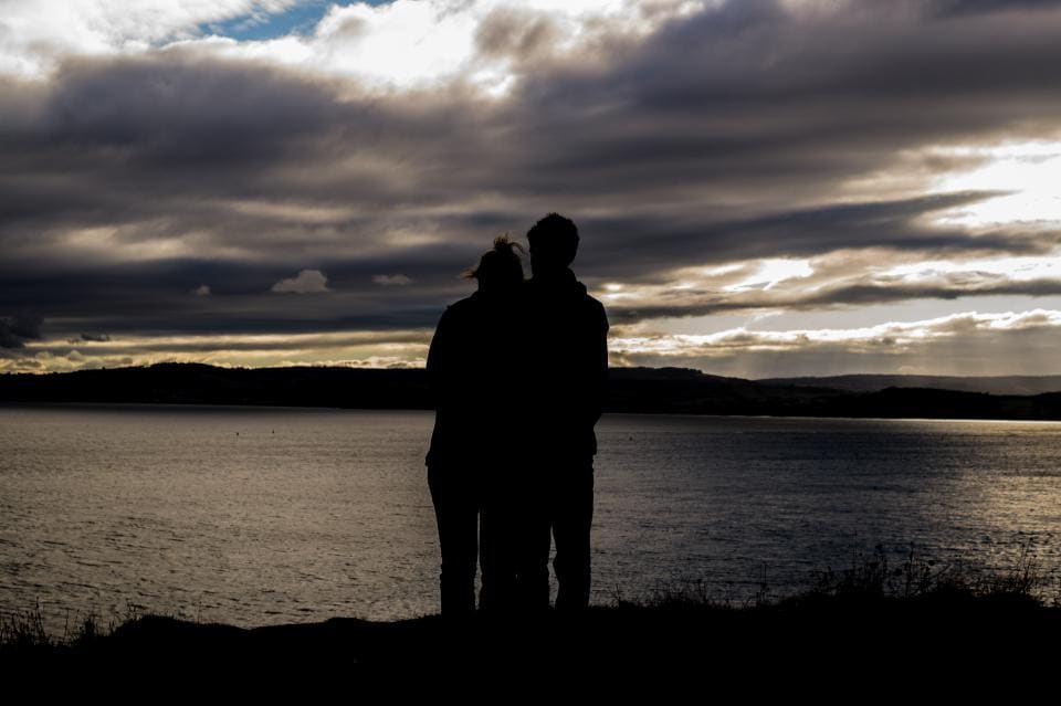 A couple by the lake watching the sunset